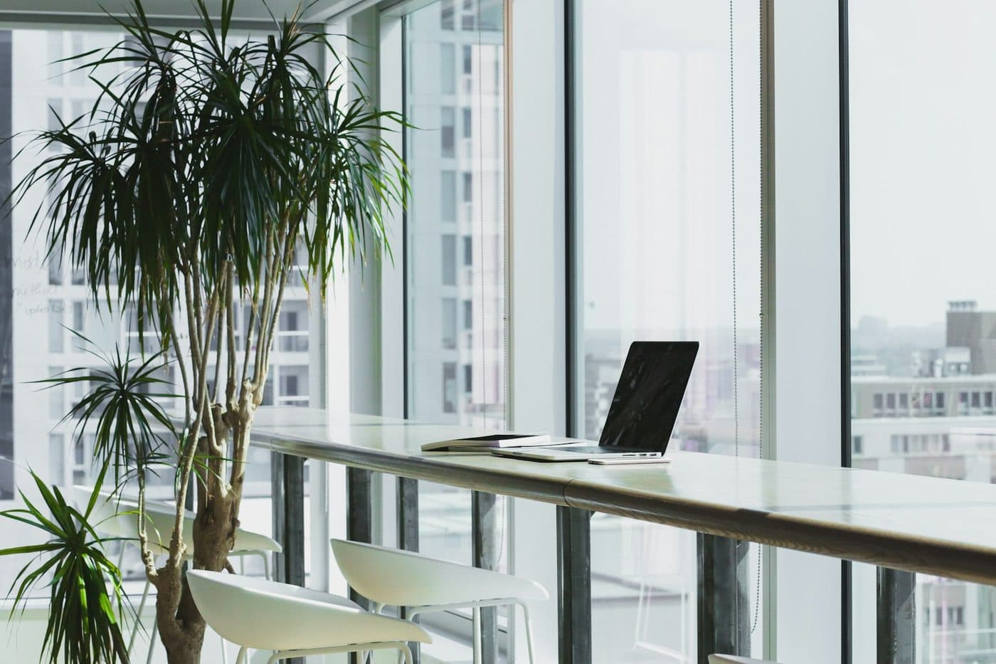 Bright standing-height desk by a window with a laptop on the surface