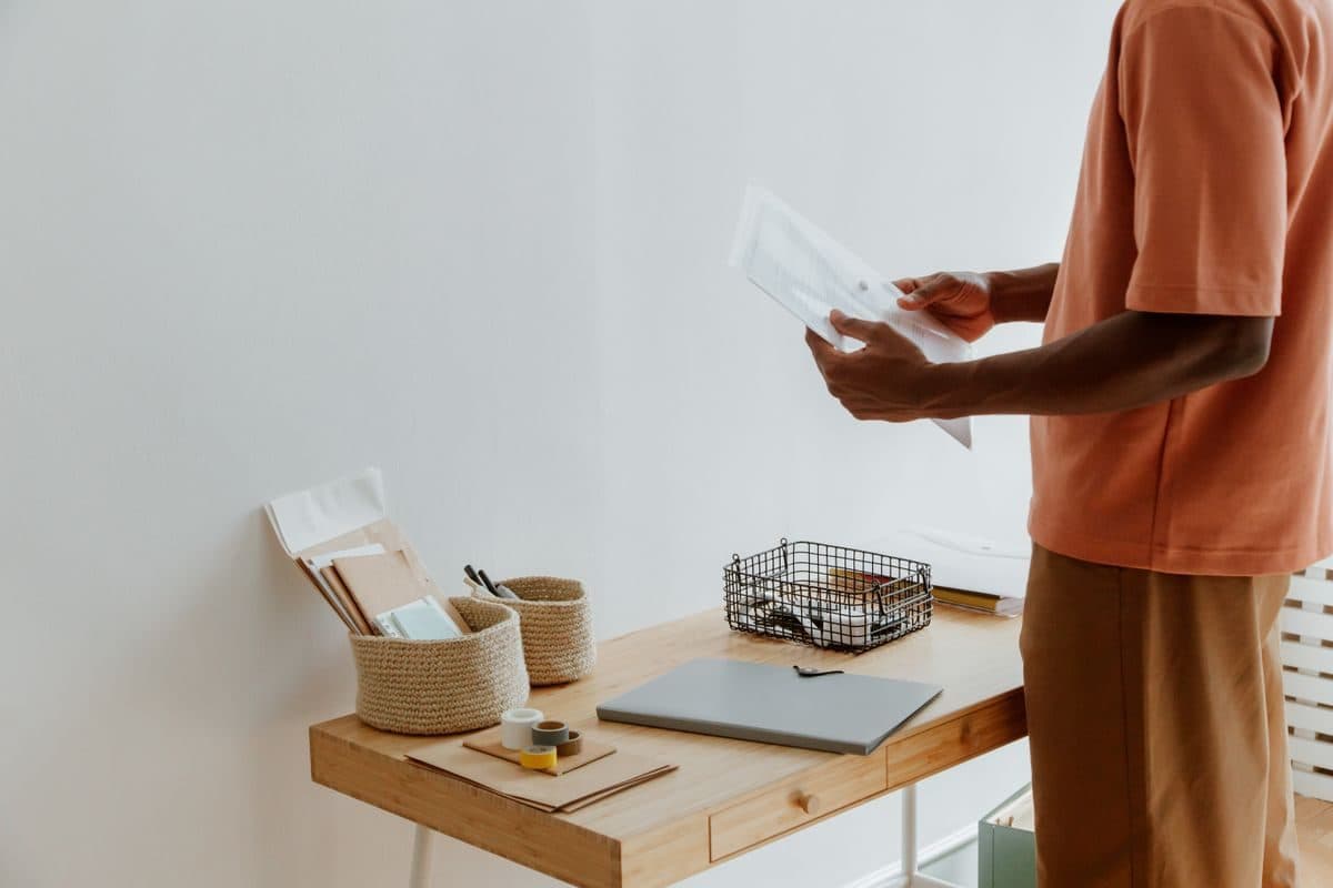 Person standing at a wooden desk reviewing papers