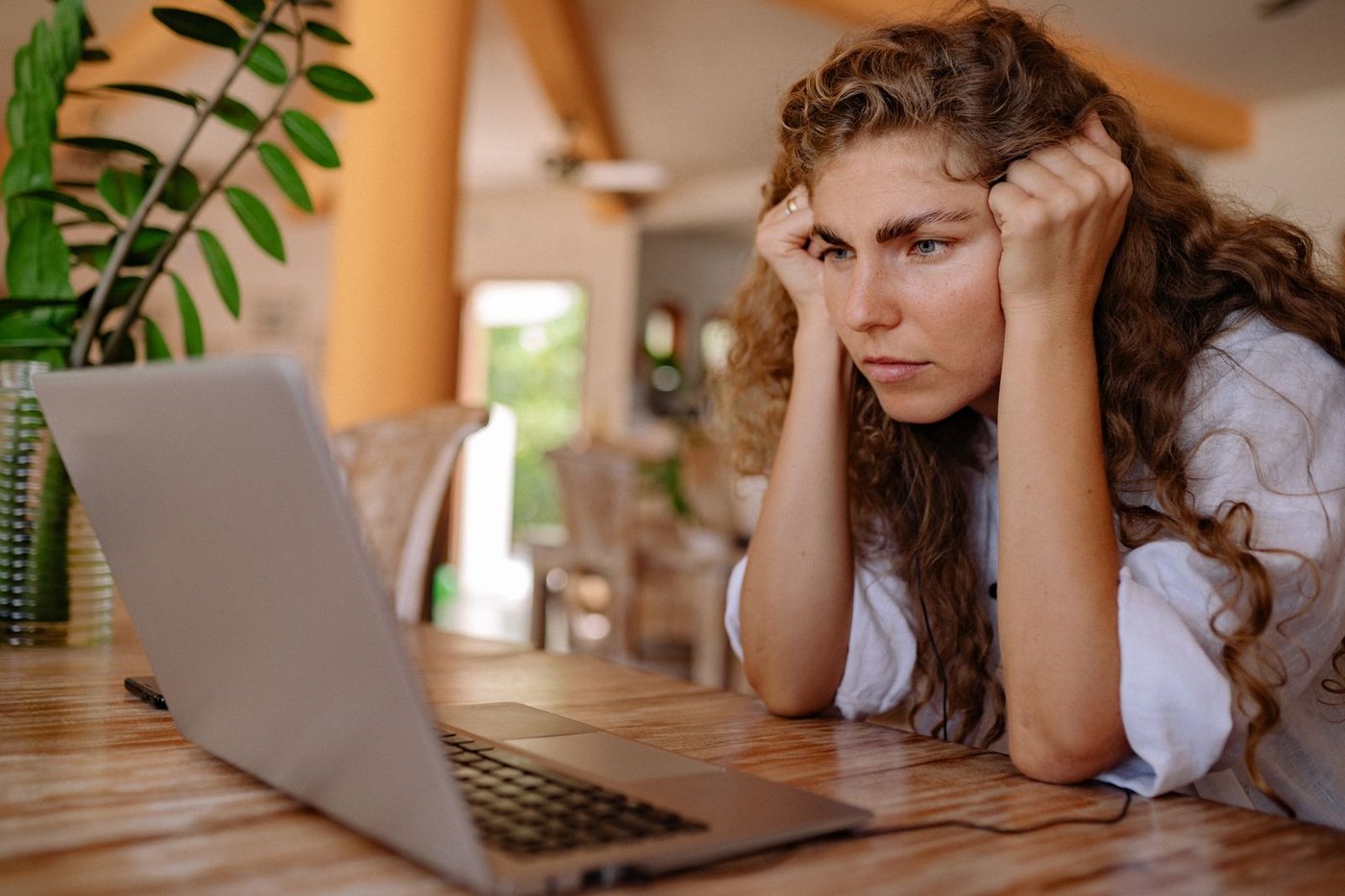 Woman leaning toward a laptop with her chin in her hands, a common too-close viewing posture
