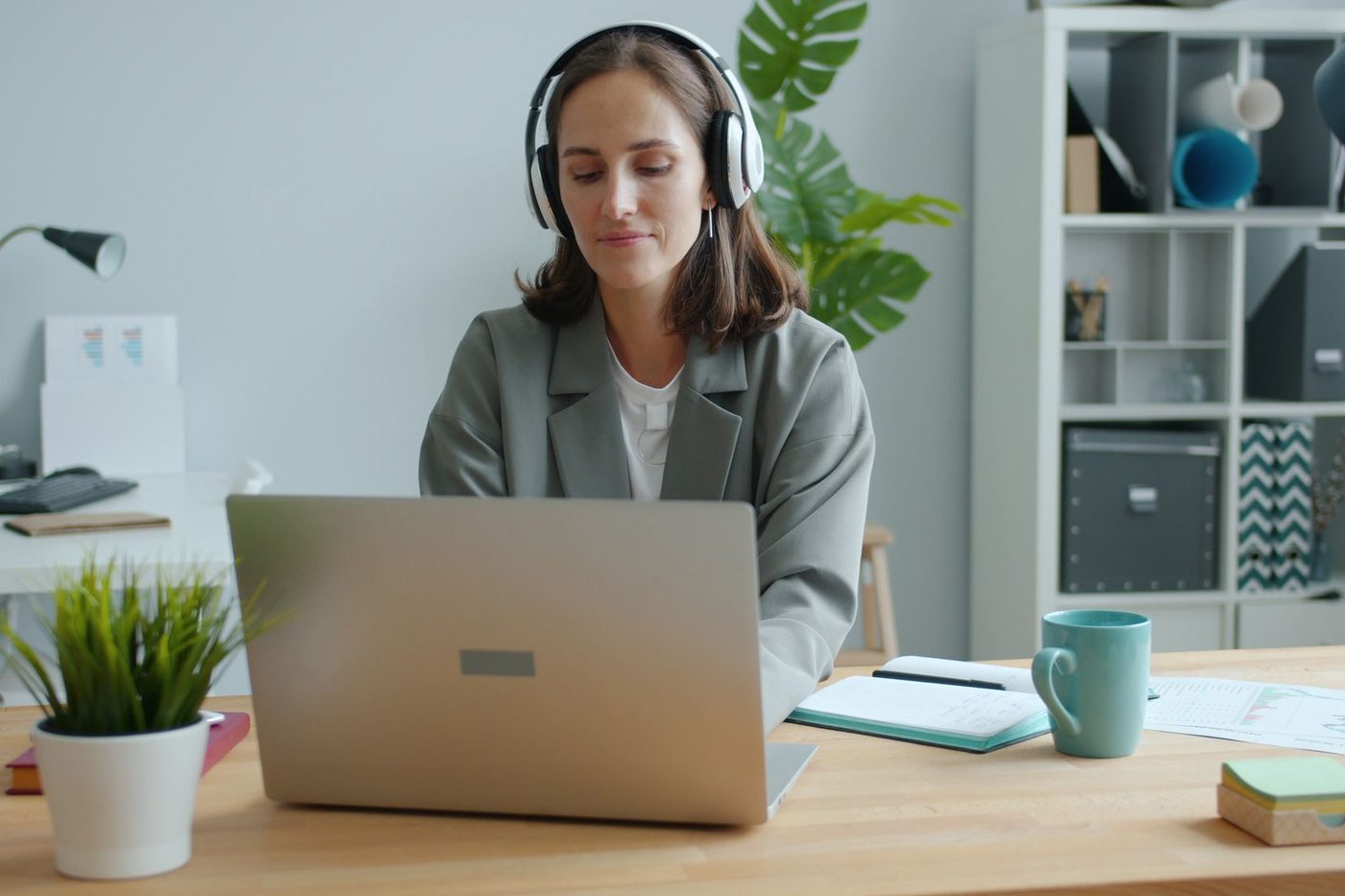 Woman working on a laptop at a wooden desk in a bright home office