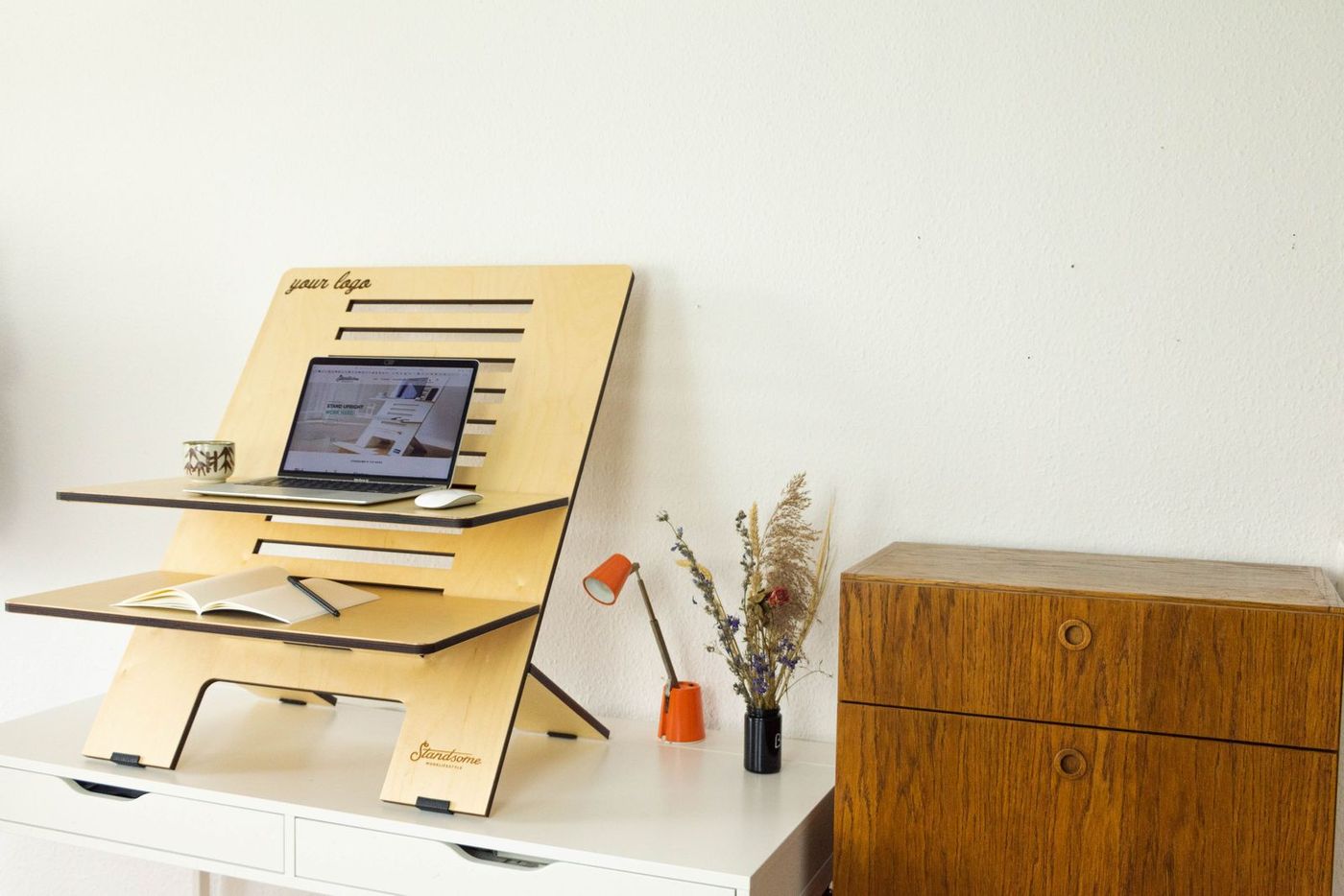 Laptop on a two-level wooden standing desk riser in a home office
